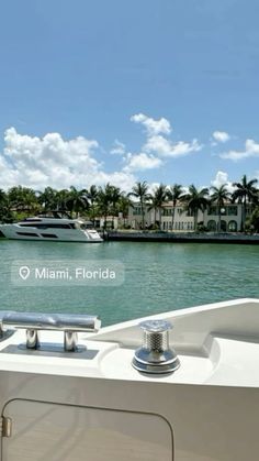 there is a boat in the water with palm trees behind it and buildings on the other side