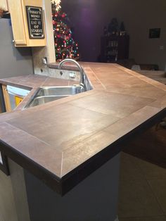 a kitchen counter top with a sink in the middle and a christmas tree behind it