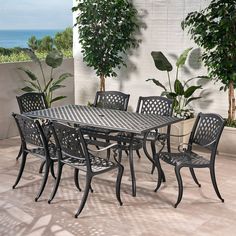 an outdoor dining table and chairs on a patio with potted plants in the background