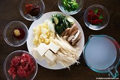 several different types of food are arranged on a white plate with clear bowls around it