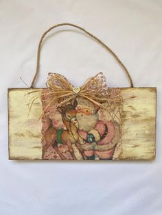 a wooden sign with a painting of santa holding a teddy bear on it's back