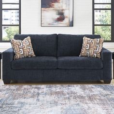 a blue couch sitting in front of a window with two pillows on top of it