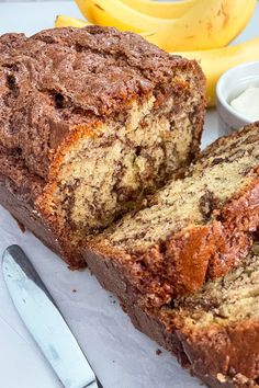 a loaf of banana bread sitting on top of a cutting board next to some bananas