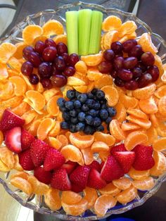 a fruit platter with celery, oranges, strawberries and grapes