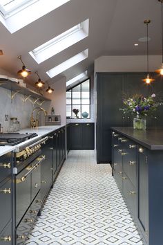 an elegant kitchen with skylights and gold trim on the counter tops, along with black cabinets