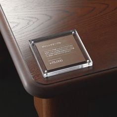 a plaque is placed on the edge of a wooden desk with metal trimmings