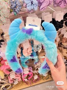 a person holding up a blue and purple furry animal headband