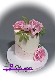 there is a white cake with pink flowers on the top and green leaves on the bottom