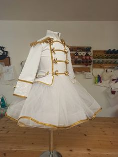 a white dress with gold trims on top of a wooden table in a room