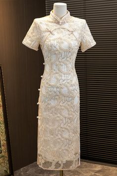 Introducing the stunning short sleeves white lace qipao with delicate floral appliques and faux pearls, a true masterpiece in traditional Chinese fashion. This gorgeous dress is crafted from high-quality lace material that feels soft and comfortable against the skin.The dress features intricate floral appliques that ar Elegant Ao Dai With Intricate Embroidery For Ceremony, Elegant White Dress With Pearl Buttons, Elegant Lace Dress With Pearl Embroidery, Traditional White Short Sleeve Ao Dai, Short Sleeve Lace Dress With Intricate Embroidery, Traditional White Ao Dai With Short Sleeves, Elegant Lace Dress With Floral Embroidery And Short Sleeves, Elegant Ao Dai With Floral Embroidery, Elegant White Ao Dai For Formal Occasions