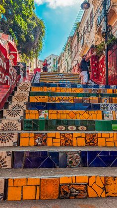 some people are walking up and down the stairs with colorful tiles on them as well as umbrellas