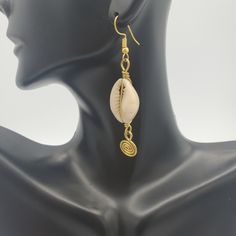 A must have pair of earrings. Dainty, but has that must needed elegant touch to it! FUN FACTS: In Africa, and in the Americas, the cowrie symbolize destiny and prosperity and in many cases hold significant spiritual and even monetary value. The cowrie was an universal form of currency whose relevance weaved into the culture of Ancient African societies. The durable and light-weight characteristics of the cowrie made them an ideal trading currency long before the world adopted pounds, dollars, or Cowry Shell Earrings, Cowrie Shell Necklace, Cowry Shell, Brass Hoop Earrings, Cowrie Shells, Seashell Jewelry, Cowrie Shell, Earrings Dainty, Brass Accents