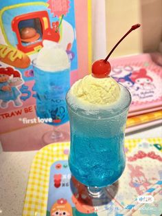 an ice cream sundae with a cherry on top sits next to children's books