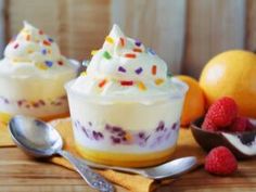 two desserts with whipped cream, fruit and sprinkles on a wooden table