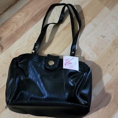 a black purse sitting on top of a hard wood floor next to a white tag