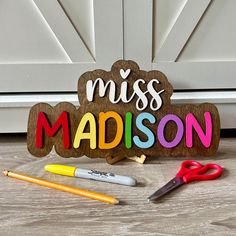 a wooden sign that says miss madison next to some markers and pencils on the floor