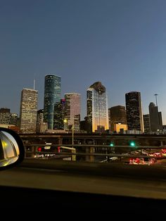 the city skyline is lit up at night as seen from a moving car in front of it