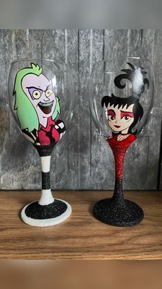 two wine glasses with cartoon characters painted on them sitting on a table next to each other