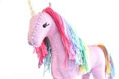 a pink stuffed unicorn with multicolored manes