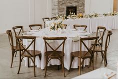 the table is set with white linens and flowers on it for a formal function