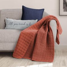 an orange and blue throw blanket sitting on top of a couch next to a pillow