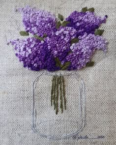 a glass vase filled with purple flowers on top of a table