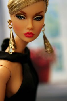 a close up of a doll with blonde hair wearing earrings and a black dress shirt