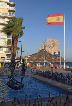 a flag flying in the wind next to a fountain