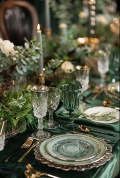 the table is set with green and gold plates, silverware, and greenery