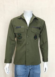 Description: Original vintage military 1981 utility shirt OG 507 poly/cotton in great condition. Washed and ready to wear. Marked size: Small , but please refer to all measurements. A: pit to pit : 50cm B: length from back neck seam to bottom back hem: 71cm C: from neck seam to bottom sleeve hem: 77cm *See last picture for details. *Please view all Detailed Pictures of the item up for offer for exact condition. *Please carefully view all size dimensions of item being offered * Vintage sizes tend Khaki Collared Utility Shirt, Khaki Military Collared Shirt, Khaki Collared Military Shirt, Olive Military Style Button-up Top, Military Style Collared Top For Streetwear, Military Style Button-up Tops For Streetwear, Military Style Collared Tops With Flap Pockets, Military Cotton Top With Flap Pockets, Military Style Long Sleeve Tops With Flap Pockets