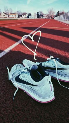 a pair of running shoes sitting on top of a tennis court next to a string