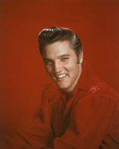 a man in a red shirt smiling and posing for a photo with his hands on his hips