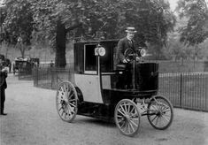 an old black and white photo of a man driving a horse drawn carriage