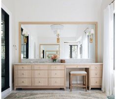 a bathroom with a vanity, mirror and stool