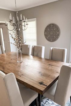 a dining room table with white chairs and a chandelier