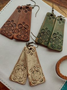 "Hand Tooled Leather Earrings tooled in a unique design...hand painted with a distressed finish.  Color choices - Off-White, Olive Green, or Chestnut. Hand painted, antiqued and finished with a protectant sheen. Nickel and lead free antique brass ear wires. Measurements are approximately 2\" L x 1\" W. Very lightweight. Would make the perfect, special gift or stocking stuffer. Treat yourself or someone you love. Handmade in my small shop in PA. Thank you for looking!!" Native American Leather Work, Tooled Leather Designs, Leather Products Ideas, Leatherworking Ideas, Tooled Leather Earrings, Handmade Leather Jewelry, Diy Leather Bracelet, Diy Leather Projects