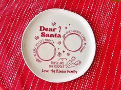 a white plate with the words dear santa on it sitting on a red table cloth