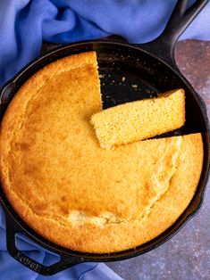 a cornbread cake in a cast iron skillet with one piece missing from it