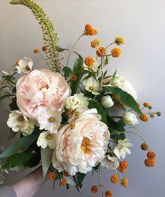 a person holding a bouquet of flowers in their left hand, with other flowers on the right