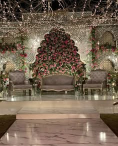 an elaborately decorated stage set up for a wedding ceremony with floral arrangements and chandeliers