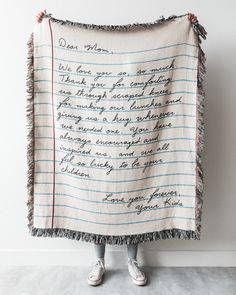 a woman holding up a blanket with writing on it