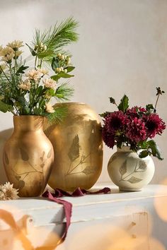 three vases filled with flowers sitting on top of a white mantle next to each other