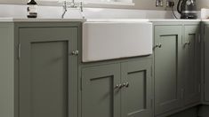 a kitchen with green cabinets and white sink in the center, along with a coffee maker on the far wall