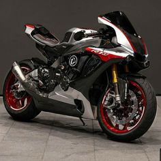 a red and silver motorcycle parked on top of a tile floor next to a wall