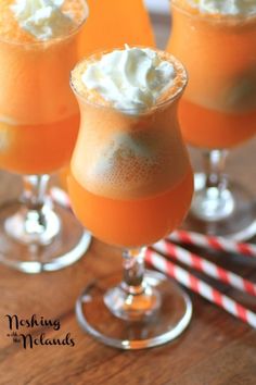 three glasses filled with orange liquid and whipped cream