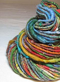 a pile of multicolored yarn sitting on top of a white table next to a bottle