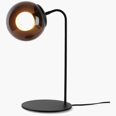 a black table lamp with a round light on it's base and a white background