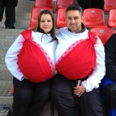 two people dressed in red and white are sitting on the bleachers with their arms around each other