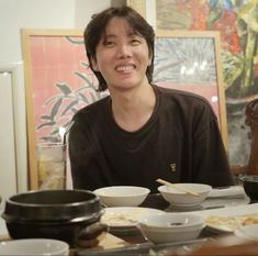 a woman sitting at a table with bowls and plates on it, smiling for the camera