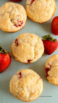 strawberry muffins and strawberries on a blue surface with the top one cut in half